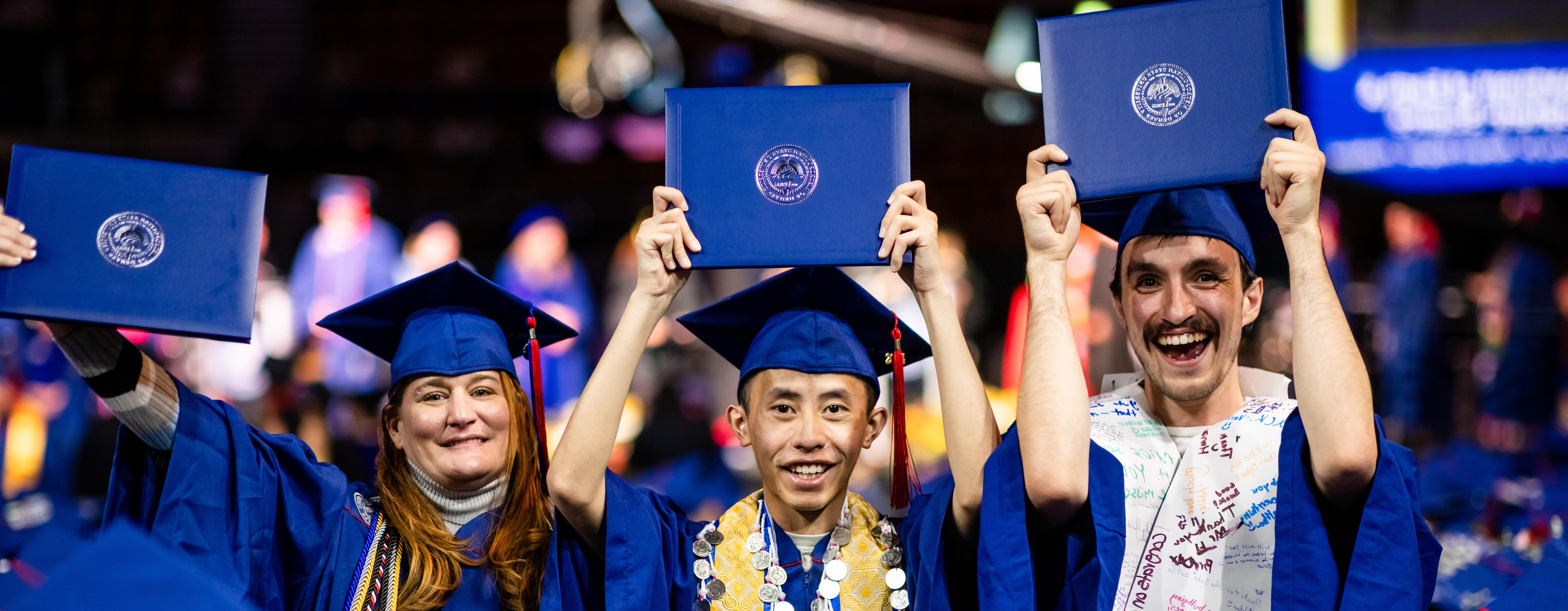 A group of graduates celebrate by holing up their diploma covers